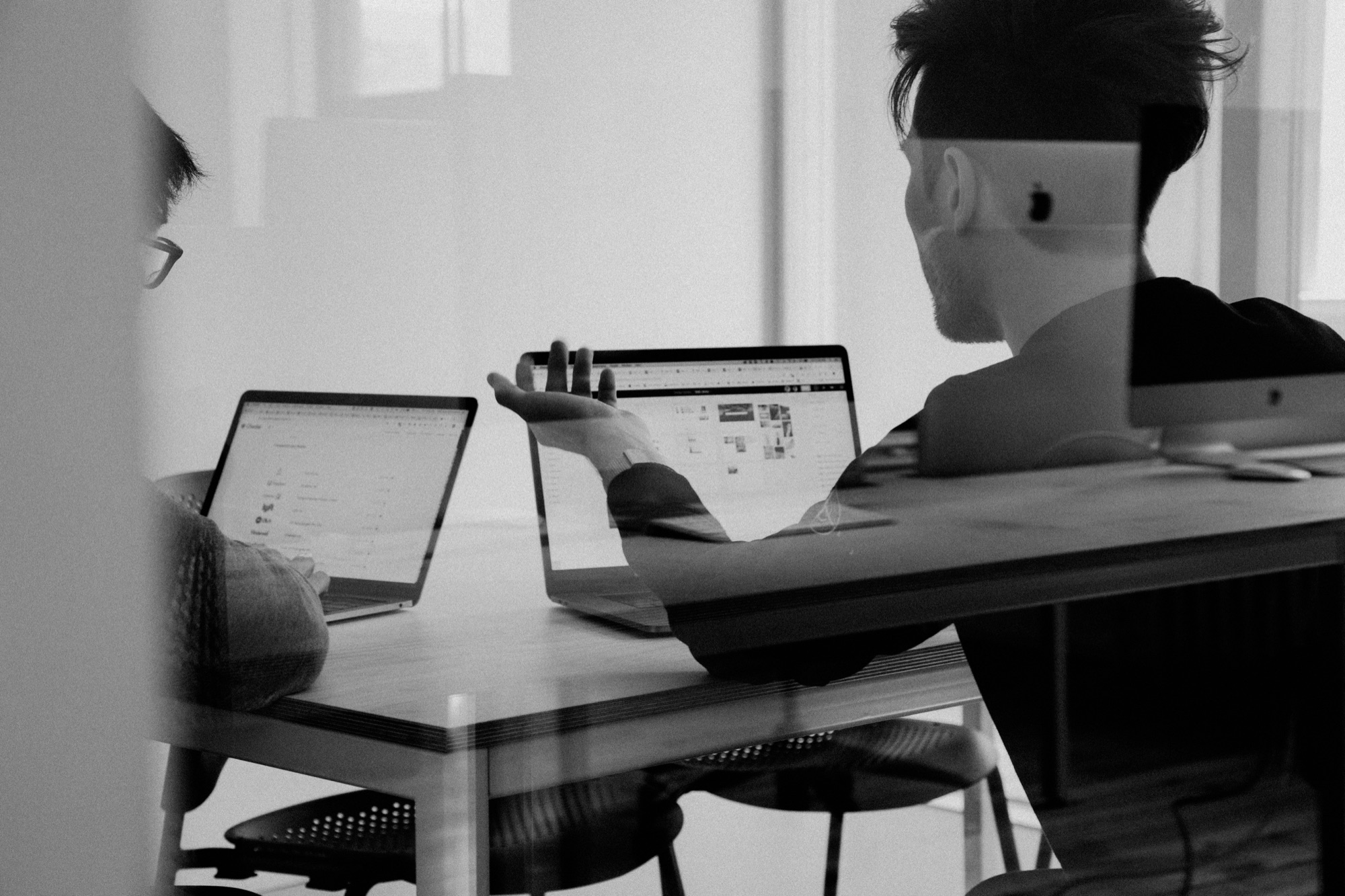 Twee mensen bespreken hun werk achter laptops tijdens een interne audit